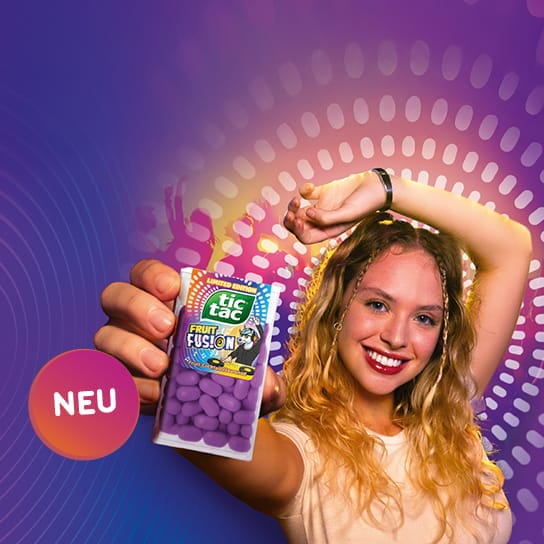 Tic Tac® Fruit Fusion Bild einer jungen, lächelnden Frau, die eine Packung Tic Tac® Fruit Fusion in der Hand hält